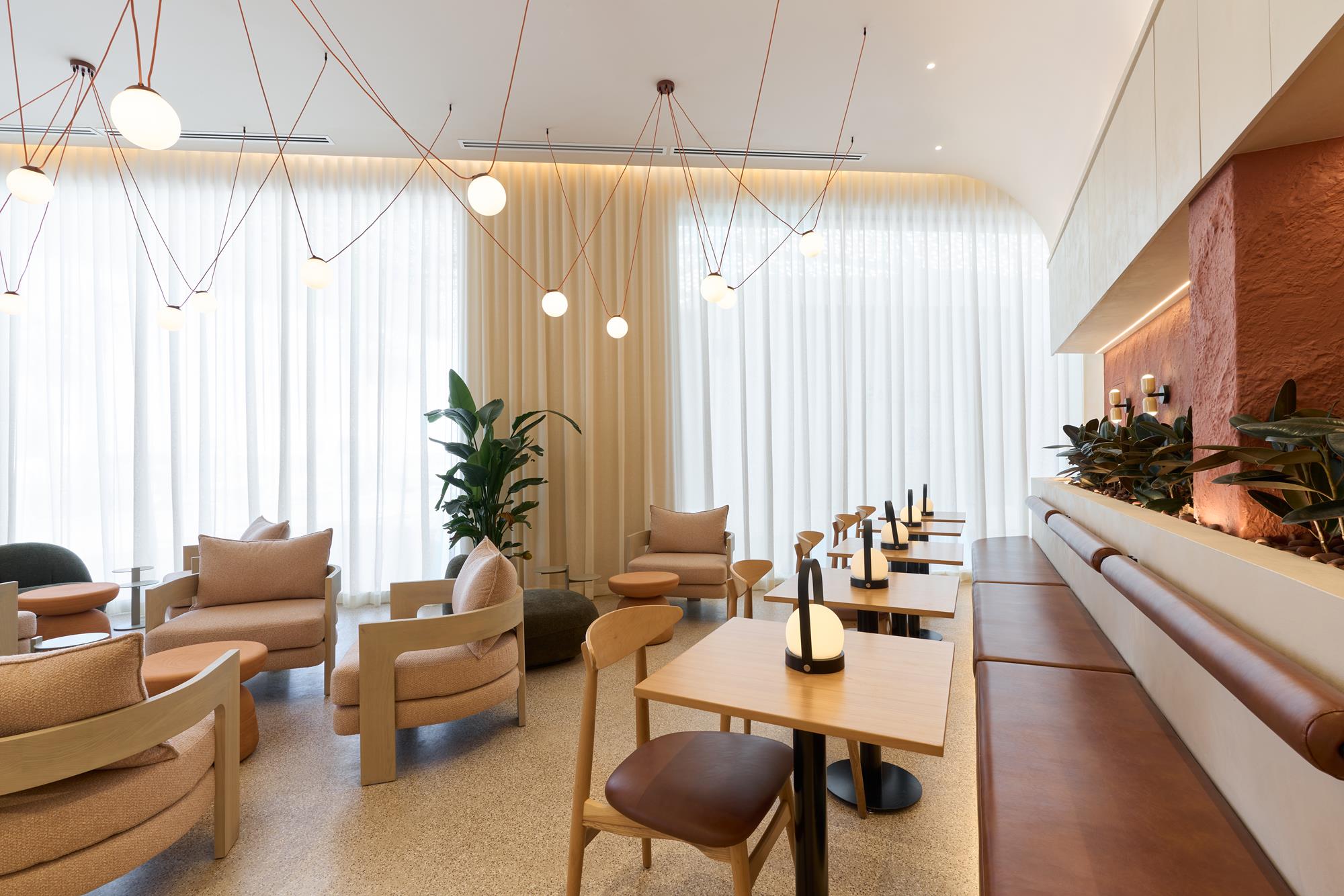 Bouclé lounge chairs facing the sheer-curtained window wall