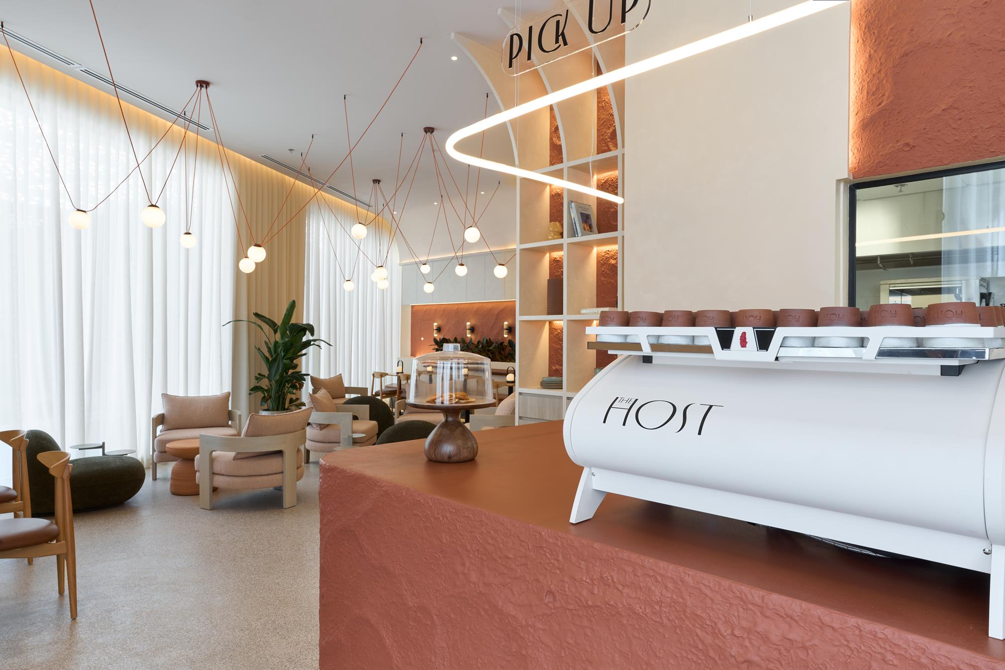 The counter and lounge together, a ribbon of light looping beneath the PICK UP sign
