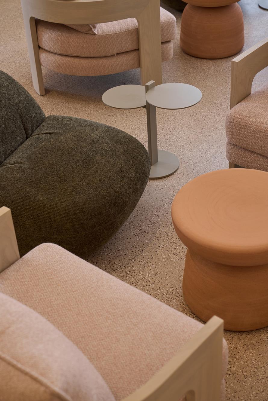 A cluster of terracotta stools and bouclé armchairs seen from above on terrazzo