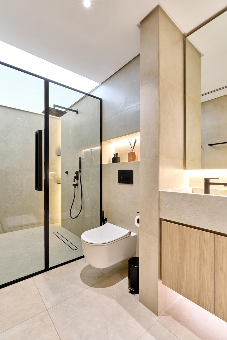 A spa-inspired bathroom in warm limestone with a stretch-ceiling skylight