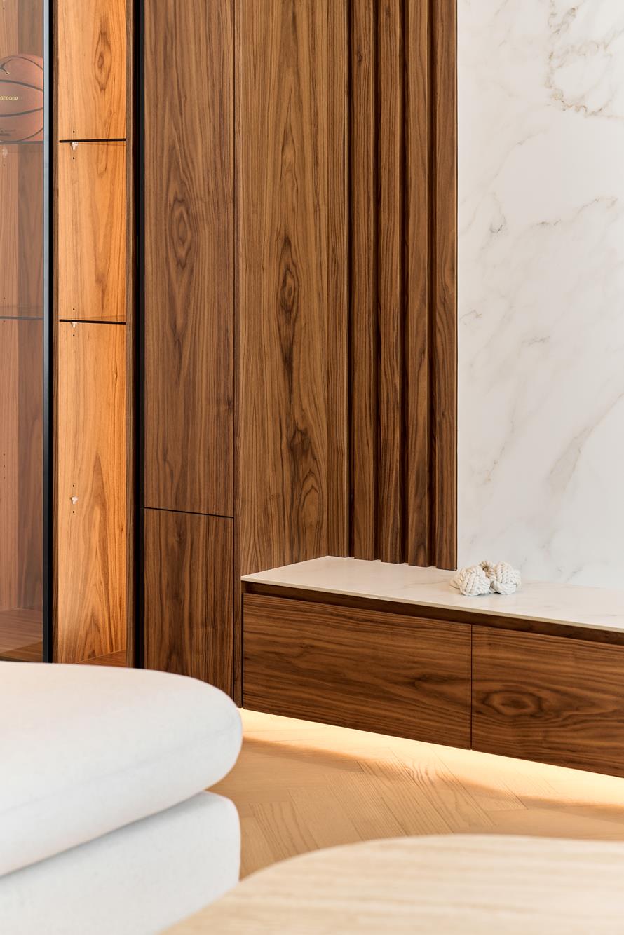 Fluted walnut joinery meeting a marble bench, lit from beneath