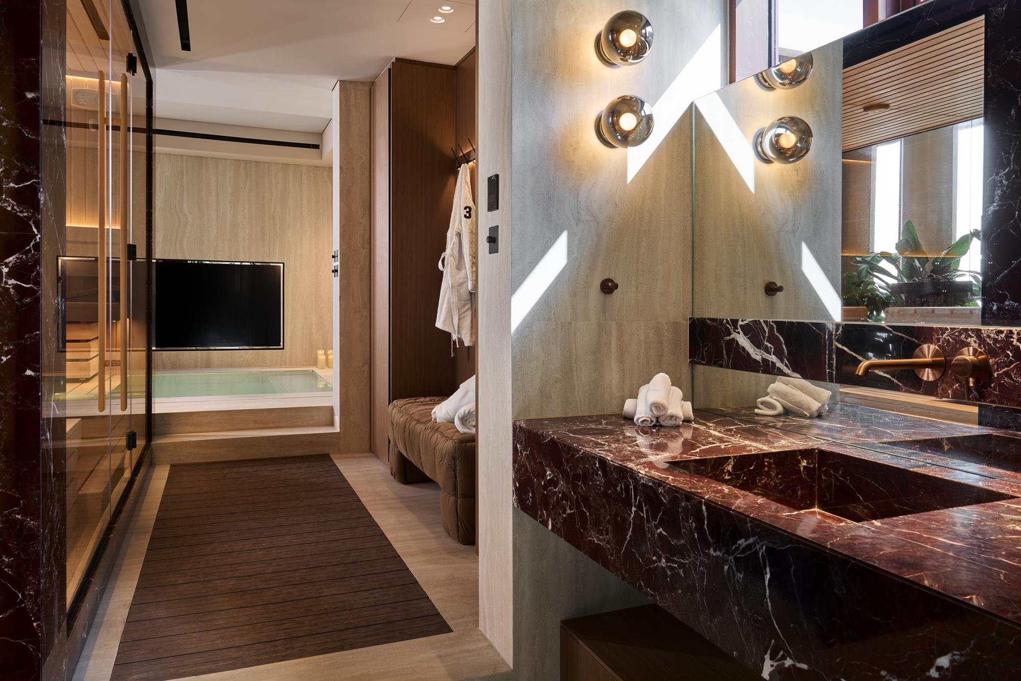 A wellness suite with burgundy marble vanity and travertine walls