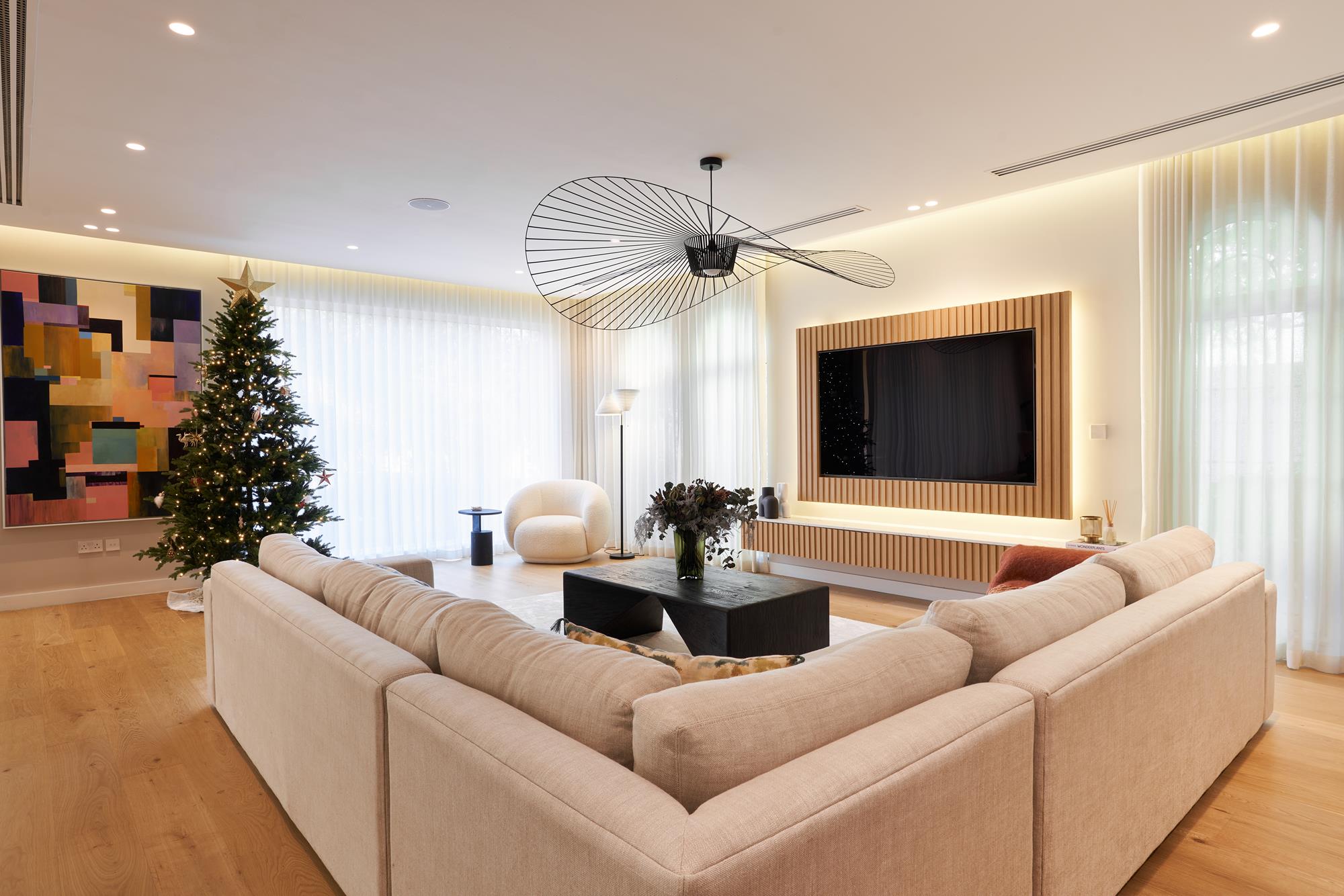 An open living room in oak and oatmeal linen beneath a wide sculptural pendant