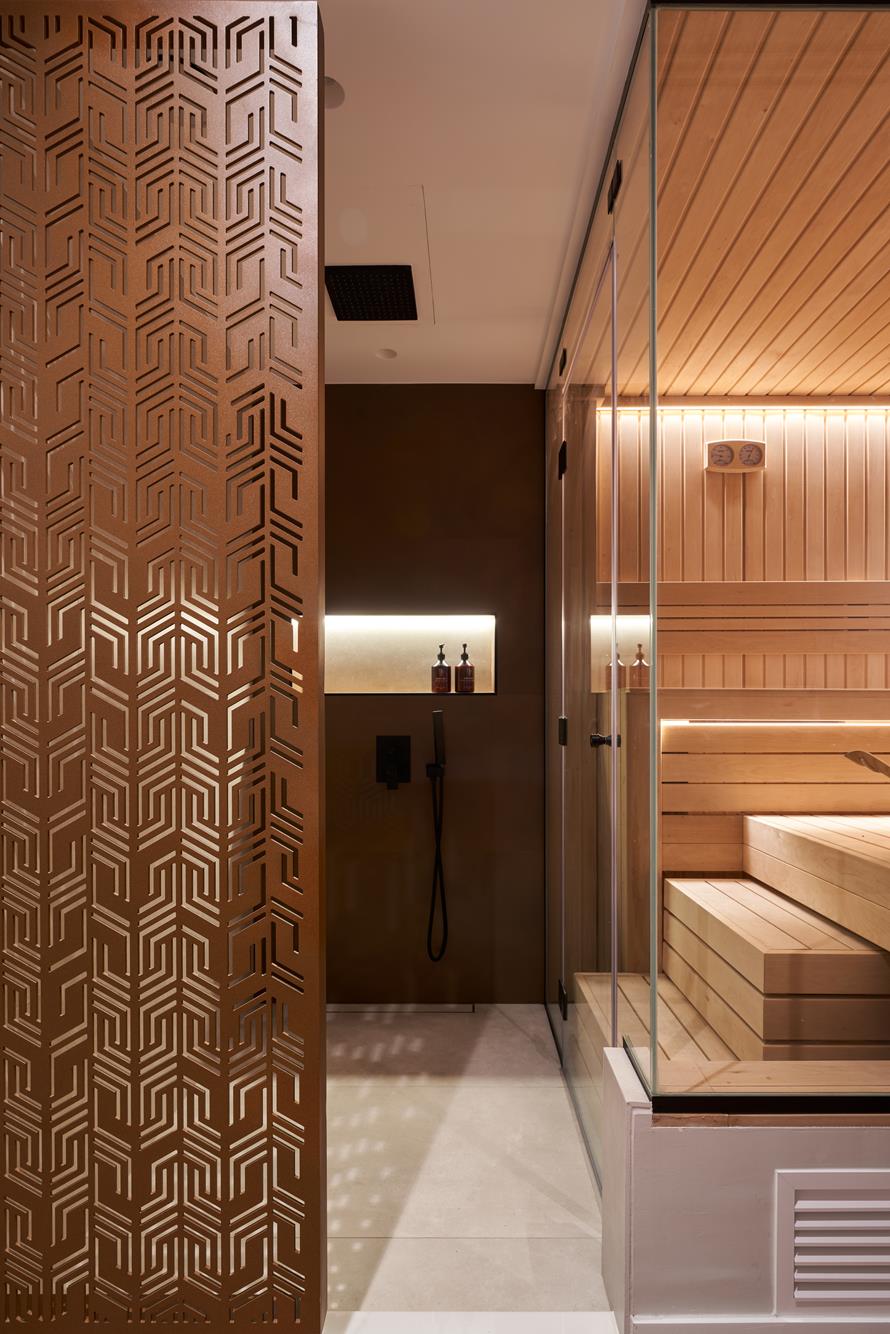 The wet room beside the sauna, a copper screen casting patterned shadow across the floor