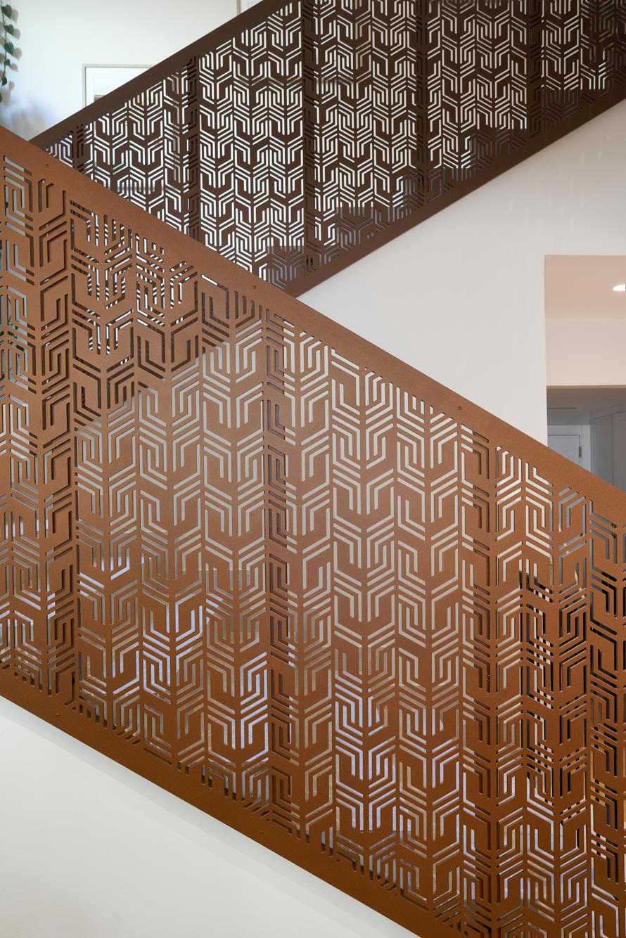 A stair balustrade cut as a copper moucharabieh screen