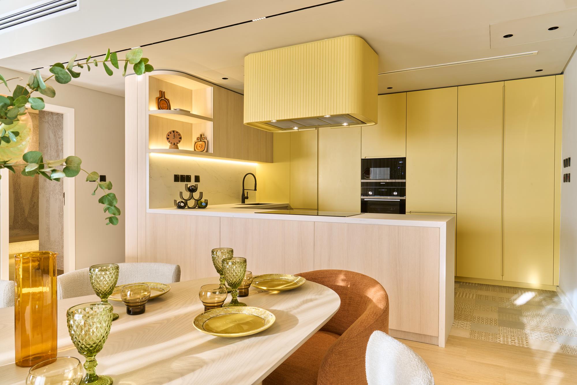 A buttercup-yellow kitchen behind a pale ash breakfast table