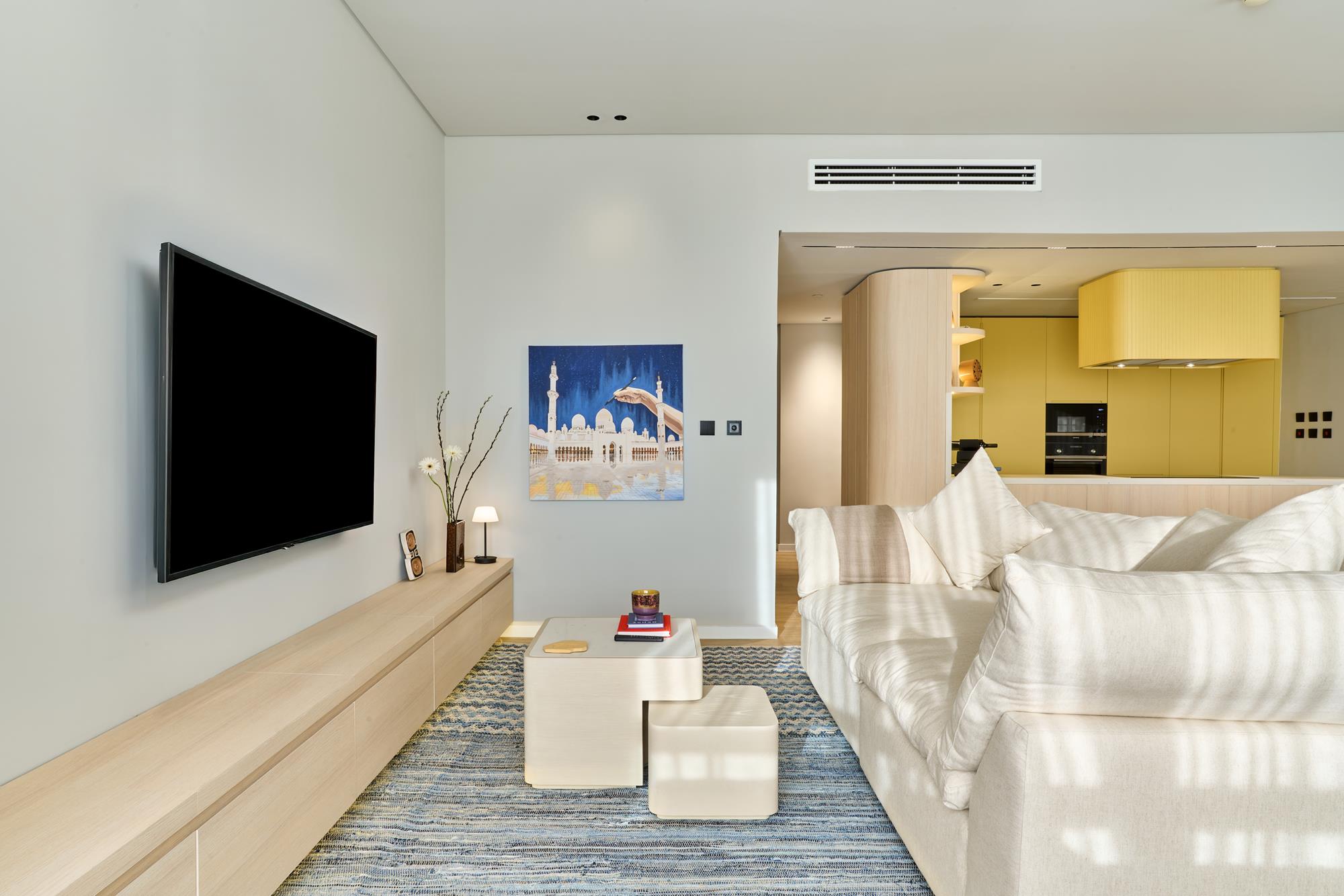 A living room where a painting of the Sheikh Zayed Grand Mosque hangs beside the kitchen threshold