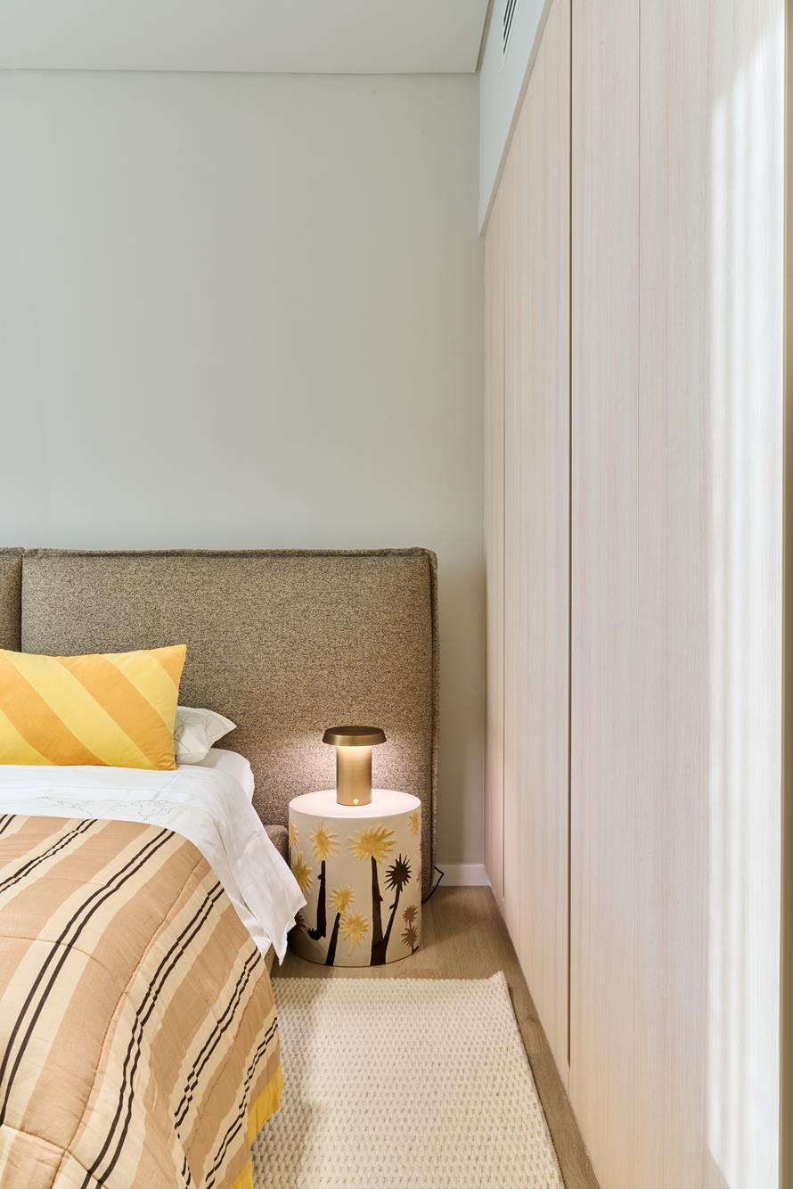 A bedside corner with brass lamp and a hand-painted ceramic side table