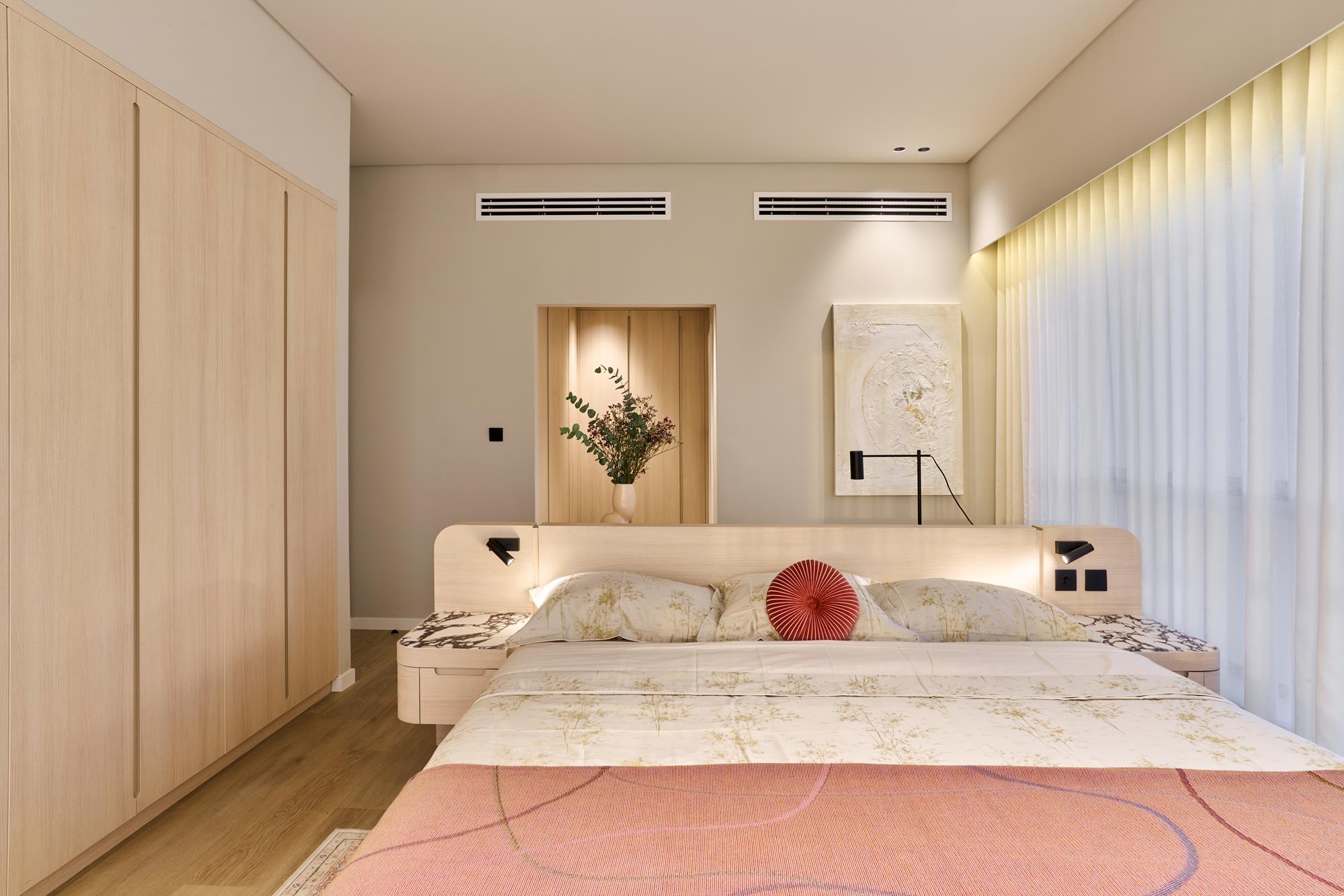 A principal bedroom in pale ash joinery with a lit headboard wall